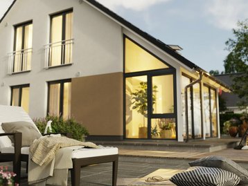 Musterhaus Bodensee 129 mit Wintergarten – Gartenansicht erleben Einfamilienhaus Bodensee 129 mit Wintergarten und großzügiger Terrasse, fotografiert aus dem Garten